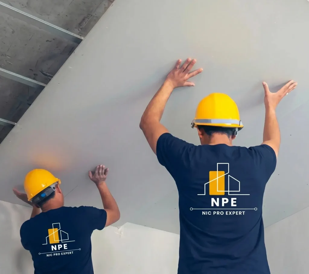 Ouvrier NIC PRO EXPERT posant une dalle de faux plafond sur un chantier